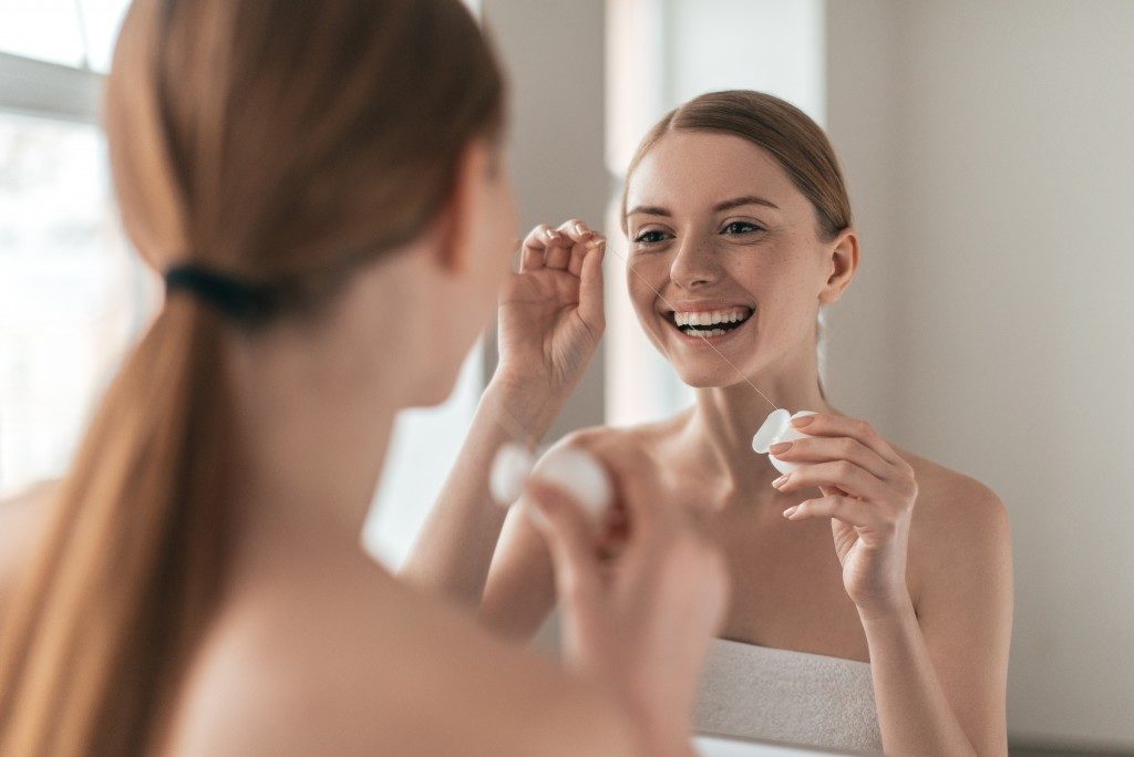 Woman cleaning her face while looking at the mirror