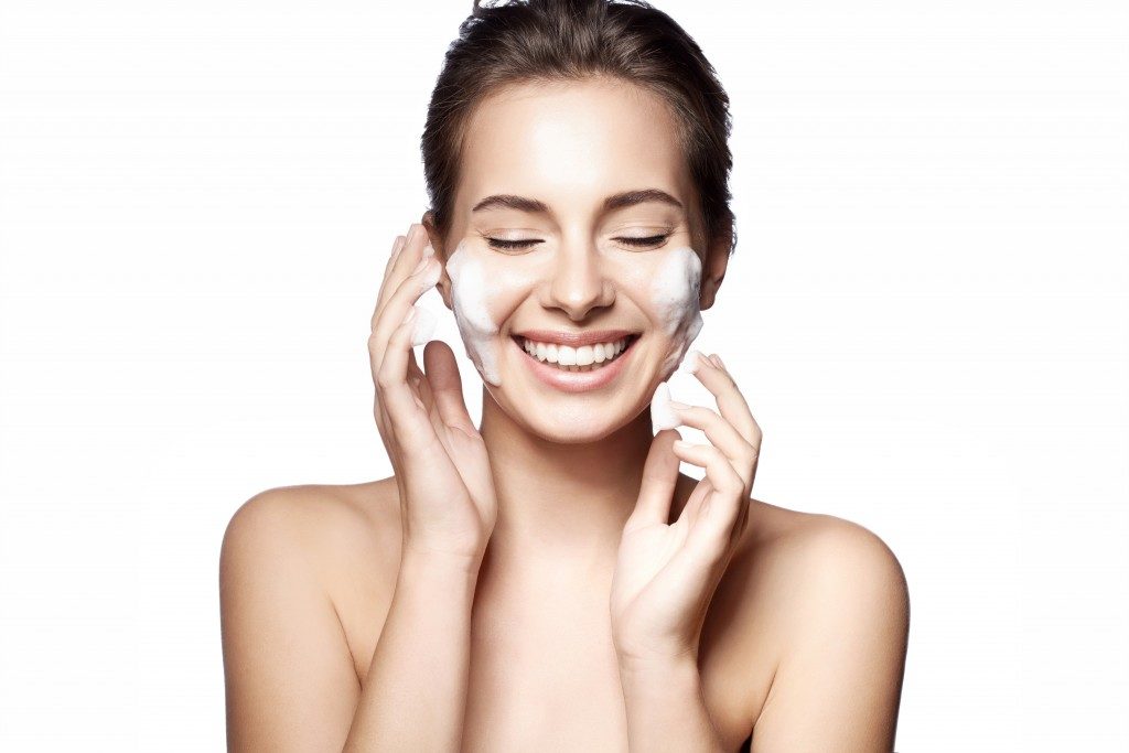 Woman cleansing her face with a white background