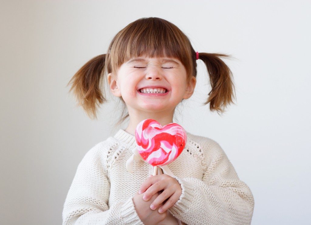 ittle girl holding a big heart-shaped lollipop