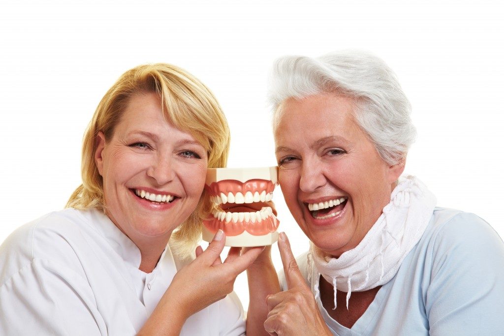 senior citizen being shown model of teeth
