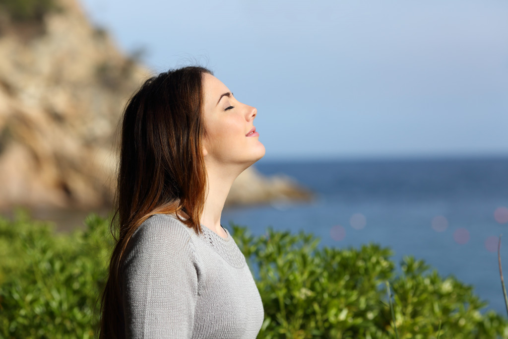 woman inhaling fresh air near the beach