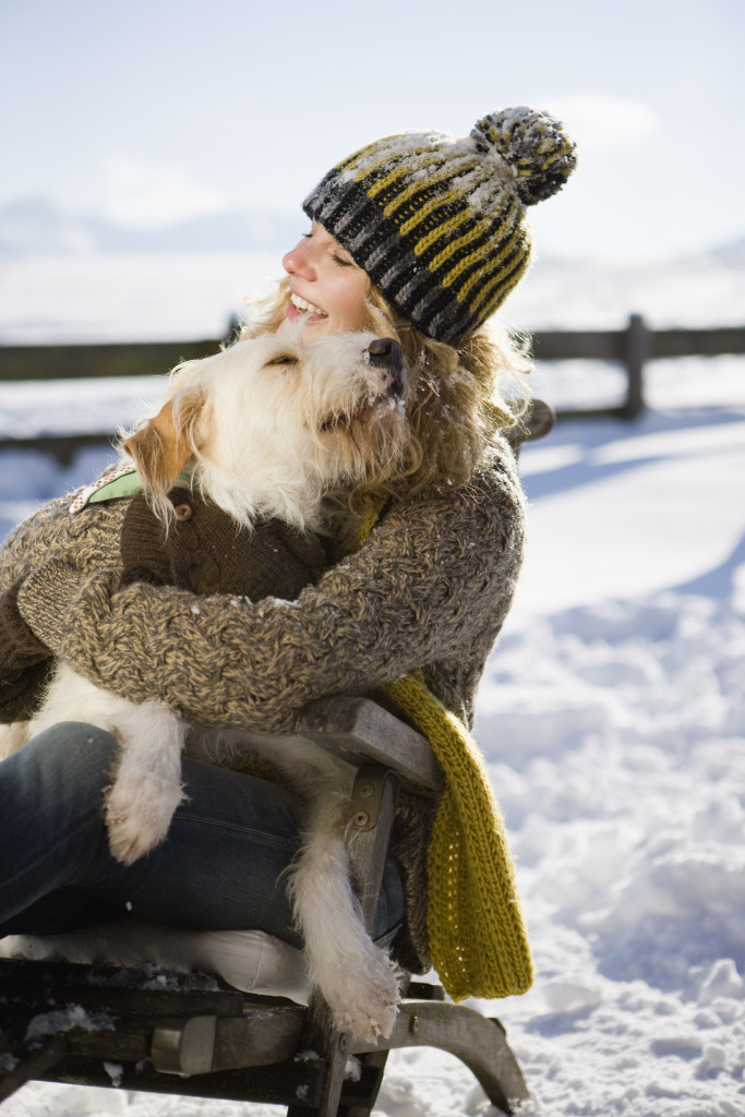 A woman embracing her pet dog in the snow