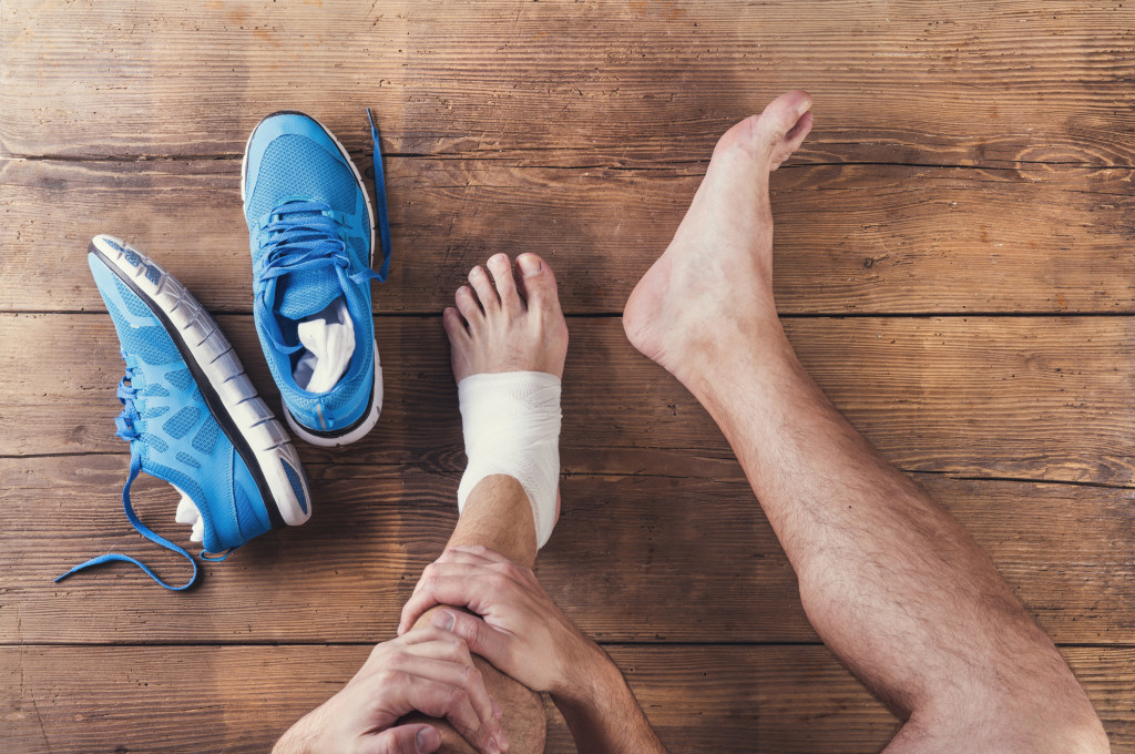 A bandaged foot of a man with his running shoes near him