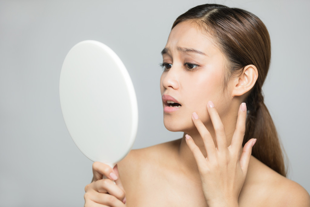 young woman looking at her skin in the mirror