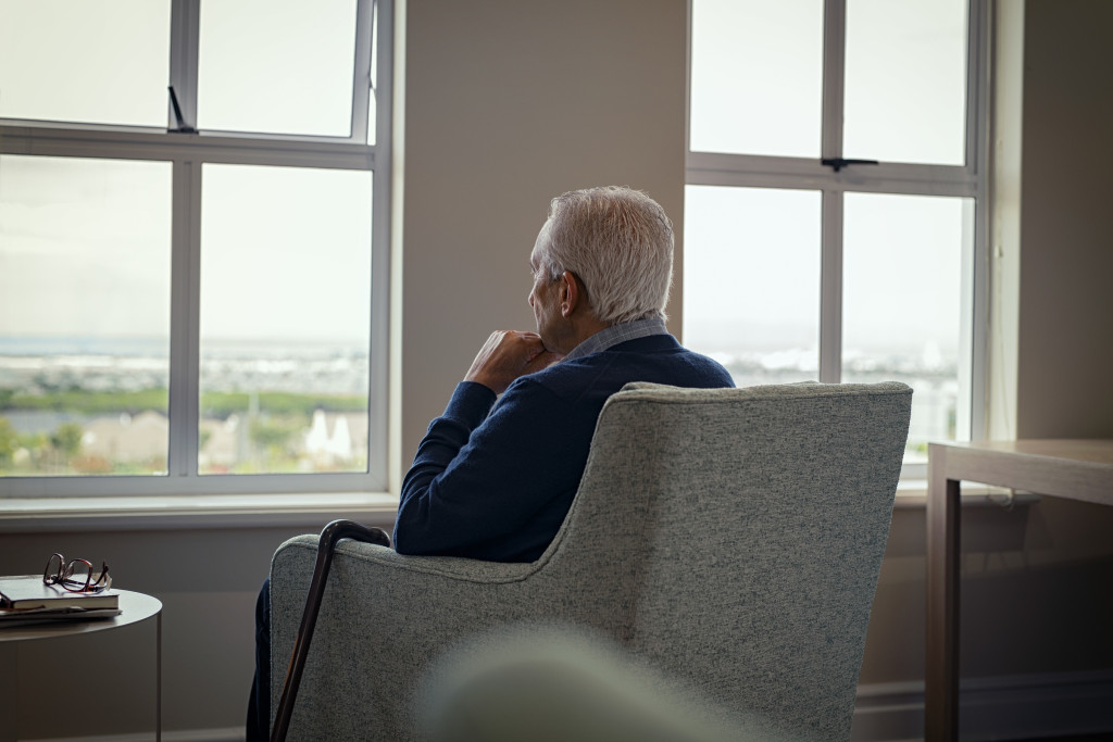 elderly man sitting beside the window