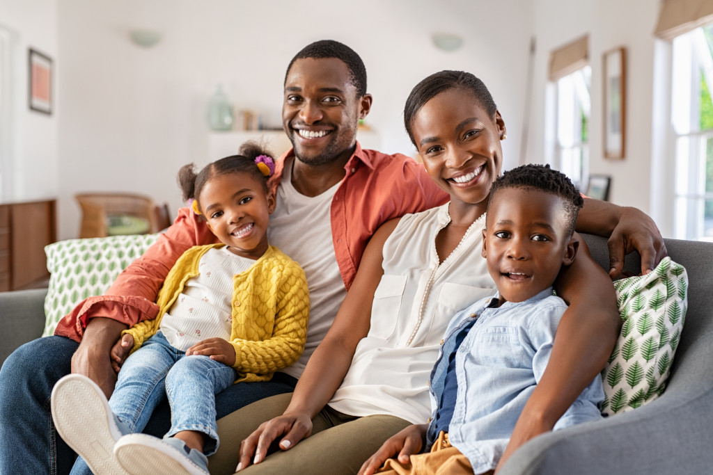Middle aged black woman with husband and children smiling and looking at camera.