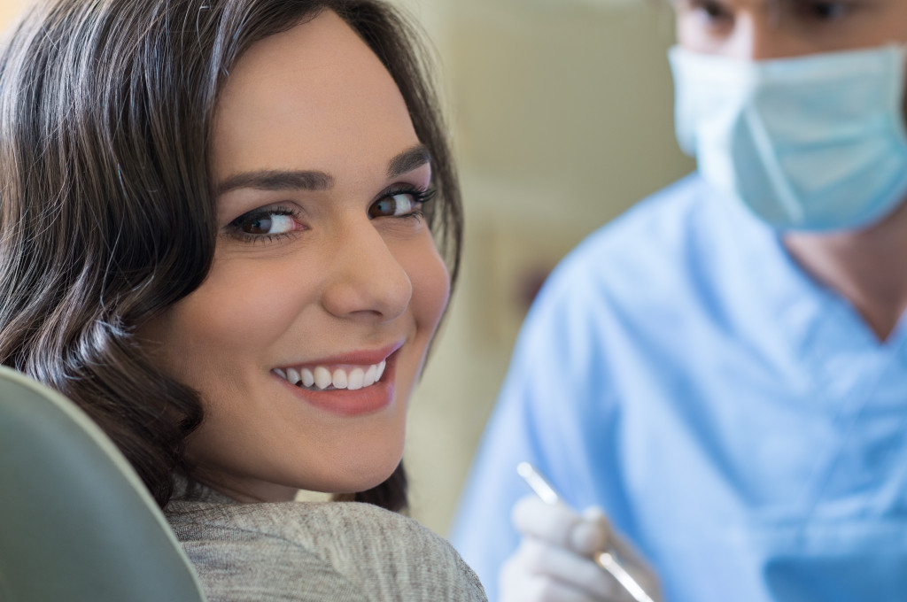 smiling female patient with dentist at the back